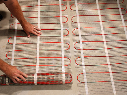 ComfortTile floor heating mats being installed for heated basement floor.