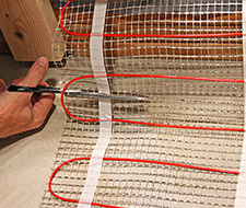 Cutting the mesh backing of floor heating mat.